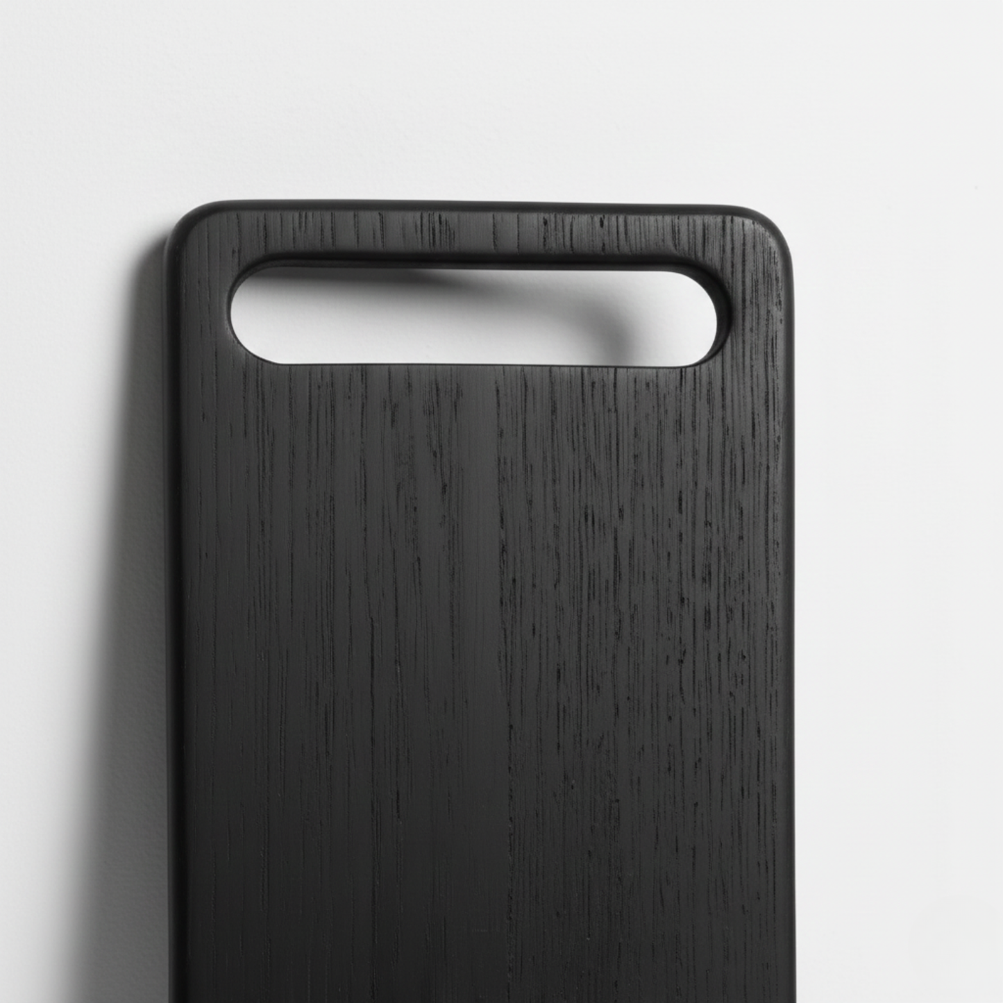 ARTSN charred black rectangular cutting board with large slot handle on light gray background