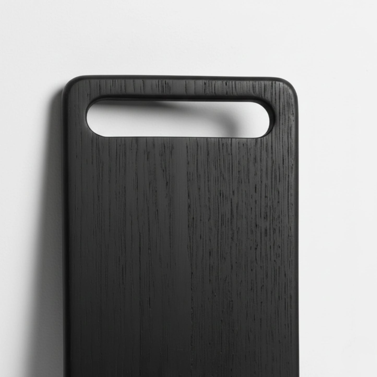 ARTSN charred black rectangular cutting board with large slot handle on light gray background