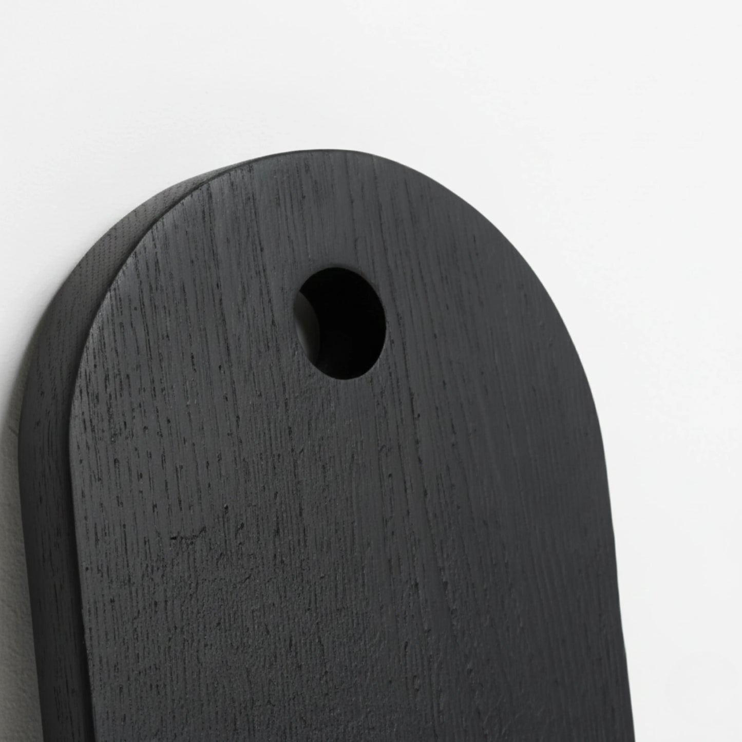 ARTSN Kura charred round black cutting board with hole for hanging on white background