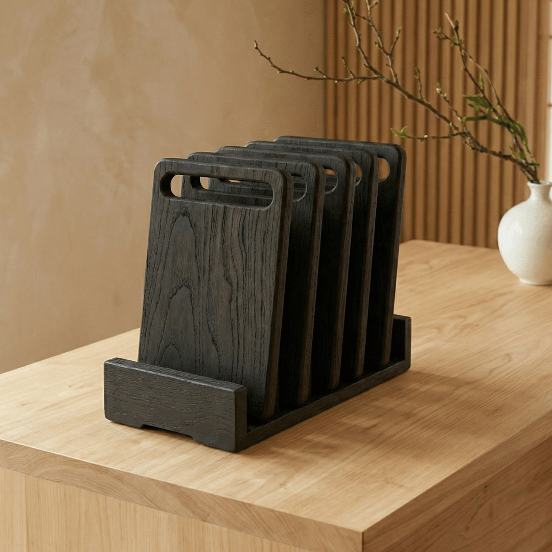ARTSN set of charred wooden cutting boards in a holder on wooden countertop with vase in background